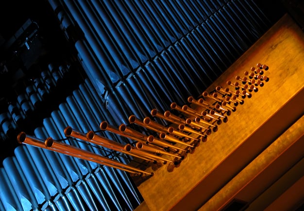 Närbild av Konserthusets orgel. Ljussatt i blått och gult sken. Fotografi.