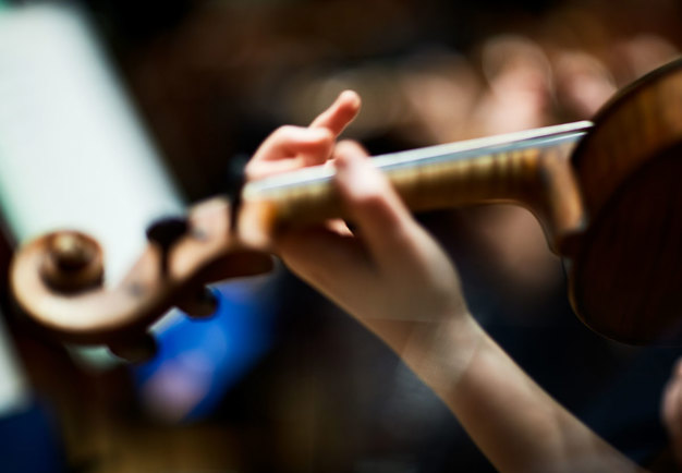 Detalj från någon som spelar på ett stråkinstrument. Fotografi. 