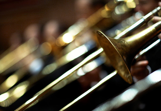 Närbild på blanka tromboner under konsert. Fotografi.