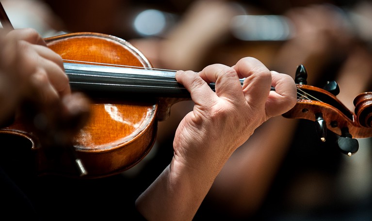 Hand som håller i en violin. Fotografi.