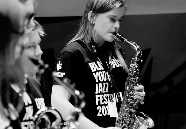 Youth playing saxofon. Black and white photo.