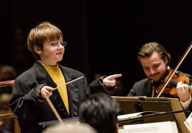 Ett barn dirigerar orkestern. Närbild. Fotografi.