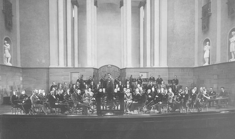 Black and white photograph of the orchestra and its conductor, from the main hall at Konserthuset.