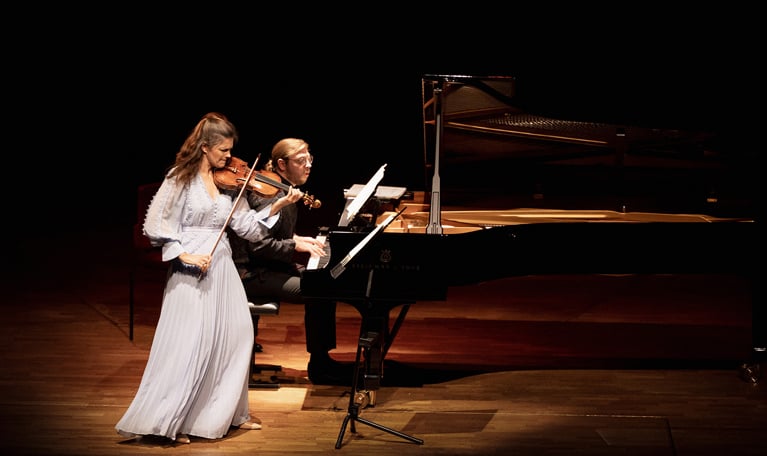 Kvinna som spelar violin och man spelar piano. Fotografi.