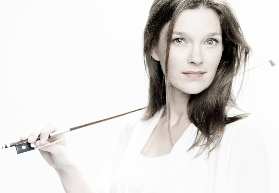 Violinist Janine Jansen looking into the camera with the bow resting on her right shoulder. Photography.