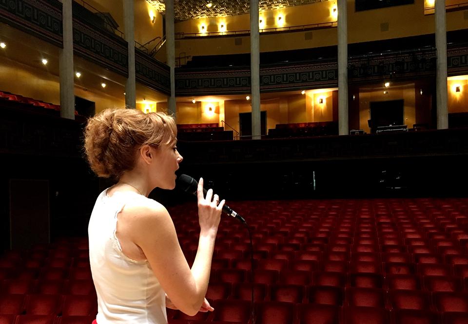 Miranda står i stora salen och sjunger. Fotograferat bakifrån.