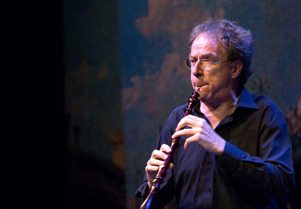 Man spelar oboe. Konserttillfällen med blåaktigt konsertljus. Fotografi.