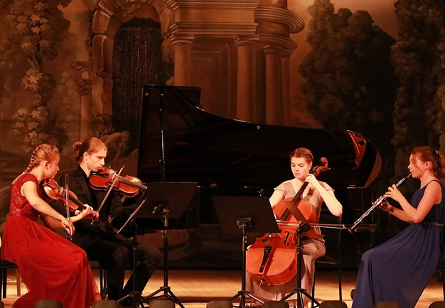 Fyra unga musiker som sitter och spelar. Fotografi