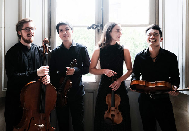 Four young musicians smiling and hold their instruments.