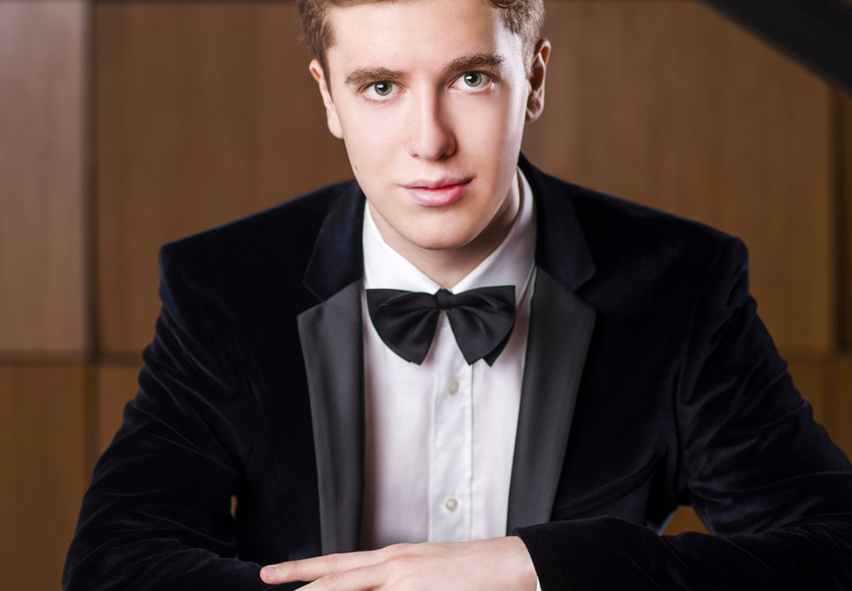 Närbild på kille som sitter vid piano. Fotografi.