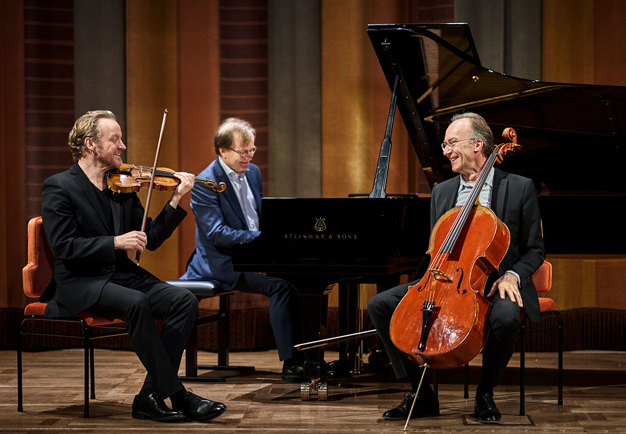 Three musicians laughing and smiling at each other.