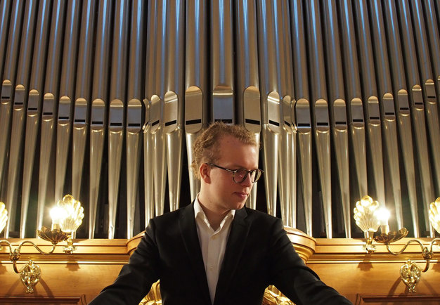 Photo of a man sitting in front of a organ.