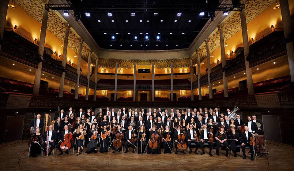 Stor orkester på podiet i Konserthuset. Fotografi