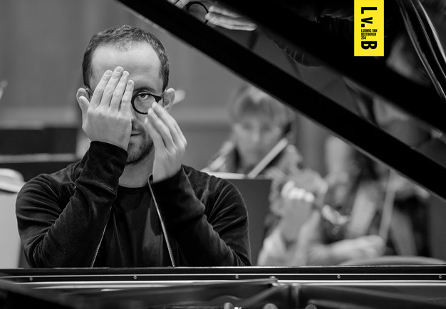 Man sitting by a piano. Photo.