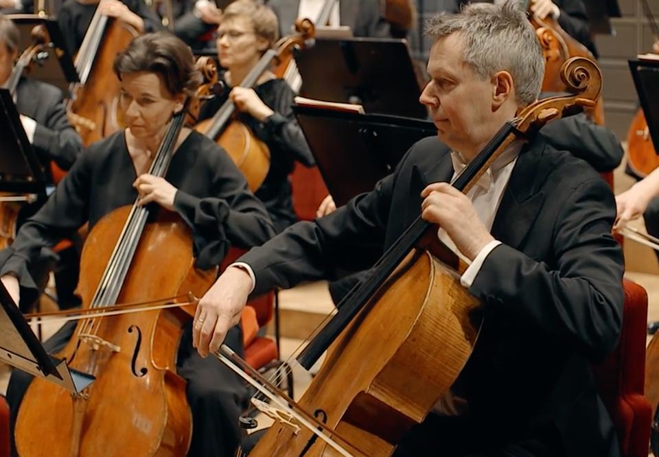 Två konsertklädda musiker som spelar cello. Konsert-tillfälle. Fotografi.