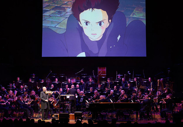 Orchestra on stage with a Ghibli video clip. Photography.