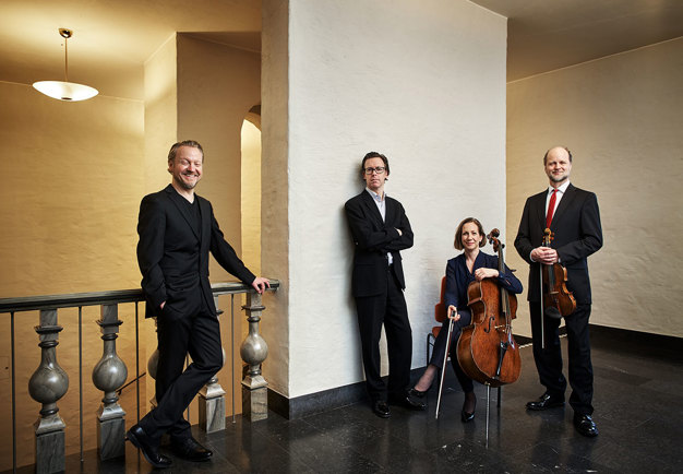 Photograph of four people dressed up in concert clothes. Group picture.