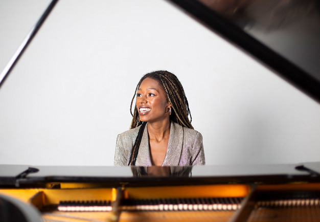 Young woman sitting by the piano. 
