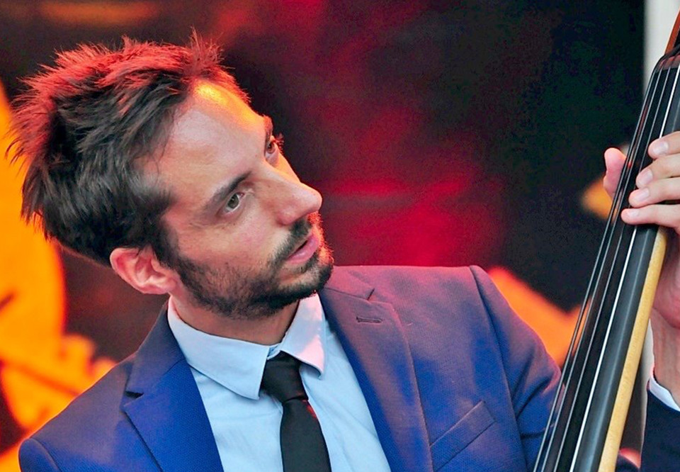 Man i blå kostym som spelar gitarr. Fotografi.