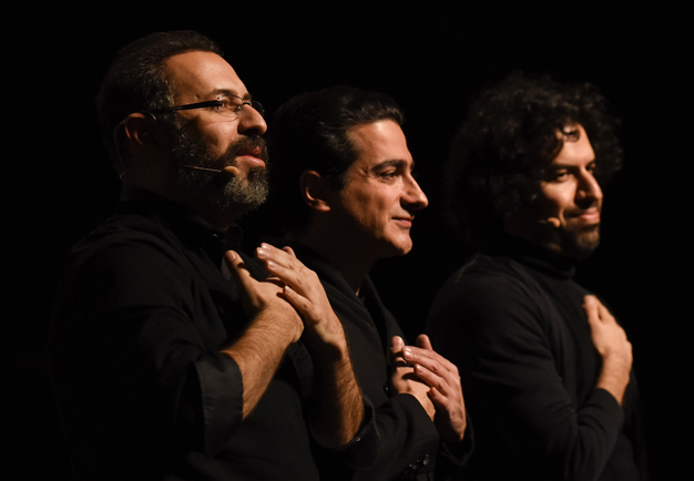 Three men in a row with dark hair and beard. Photo.