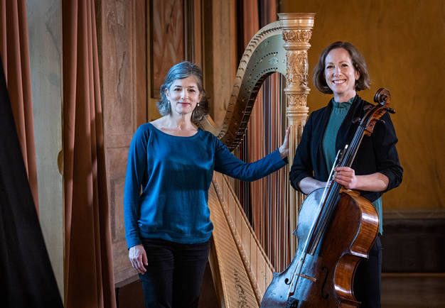 Två kvinnliga musiker. En med harpa och en med cello. Fotografi.