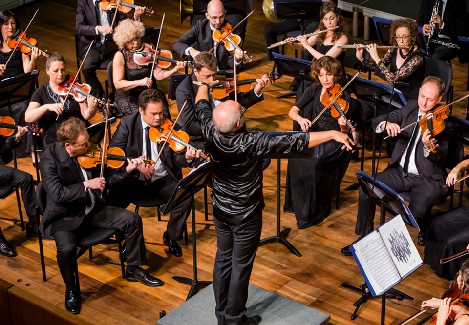 En dirigent leder en orkester på scen.