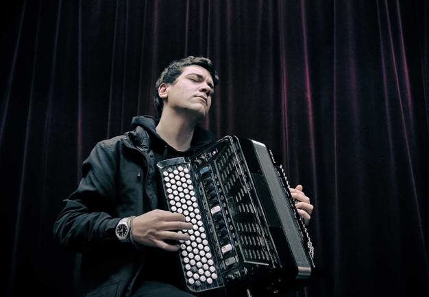 Man with black jacket holding his accordion in his hand. Photography