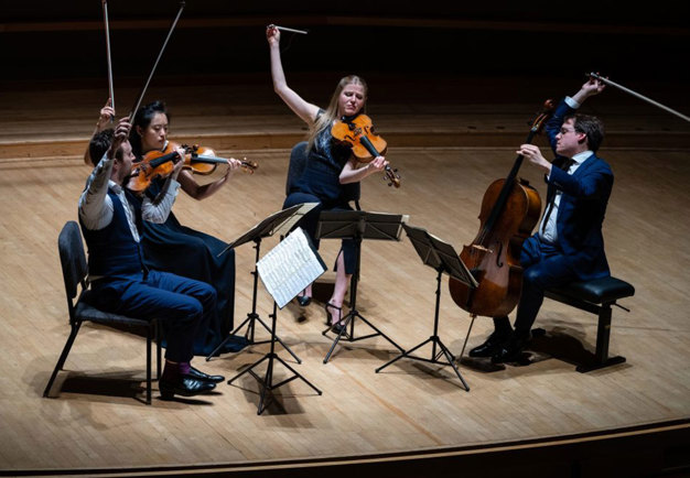 Photo of four people playing their string instruments. 