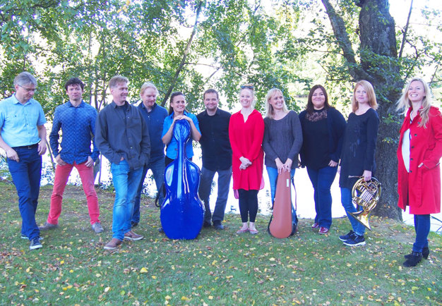 Ensemblebild på en grupp i färgglada kläder ute i naturen. Foto