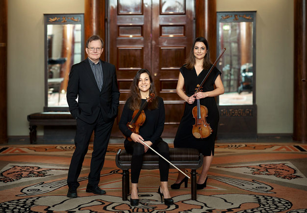 En man och två kvinnor med violiner i händerna. Gruppbild. Fotografi.