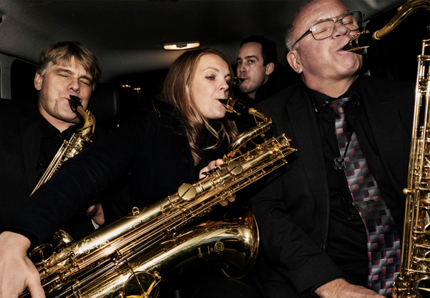 Fyra saxofonister som sitter och spelar. Fotografi.