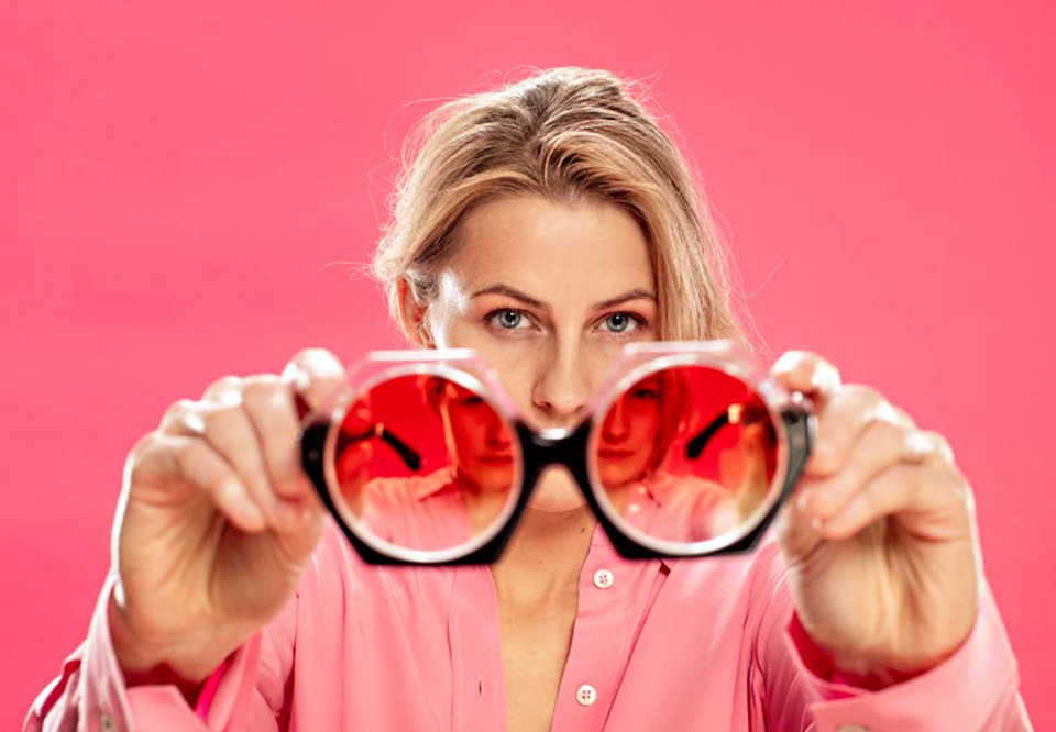 Kvinna som håler i glasögon som är rosa. Fotografi.