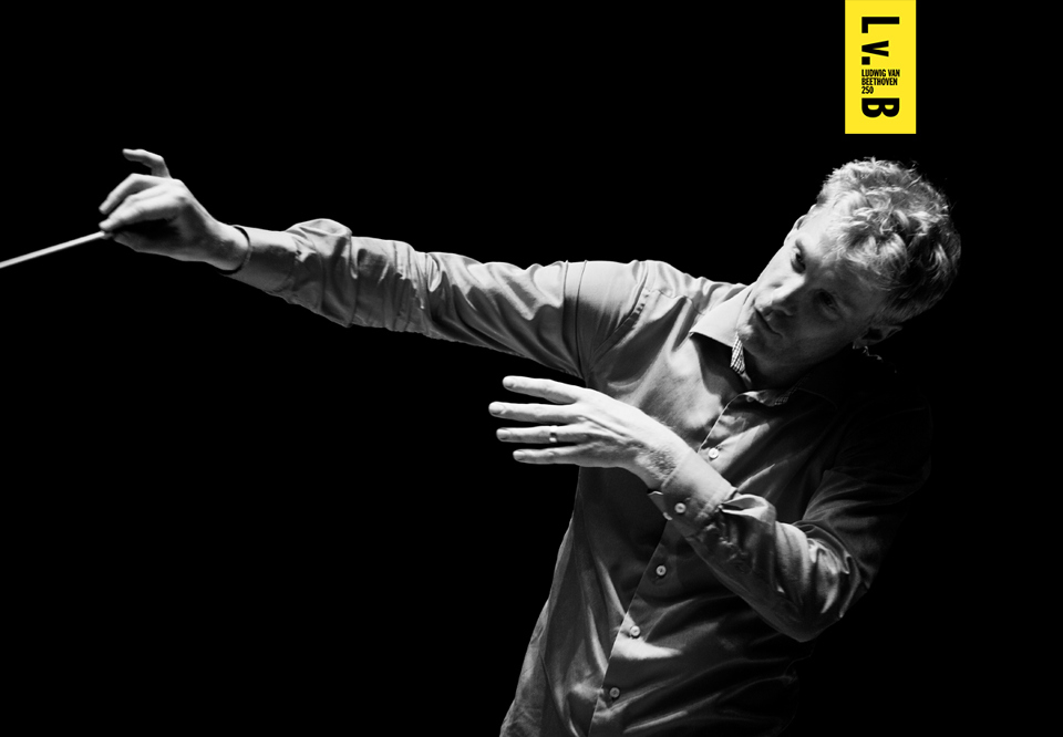Martin Fröst dirigerar, kroppen är böjd som i fångat mitt i en rörelse. Dirigentinne i handen.