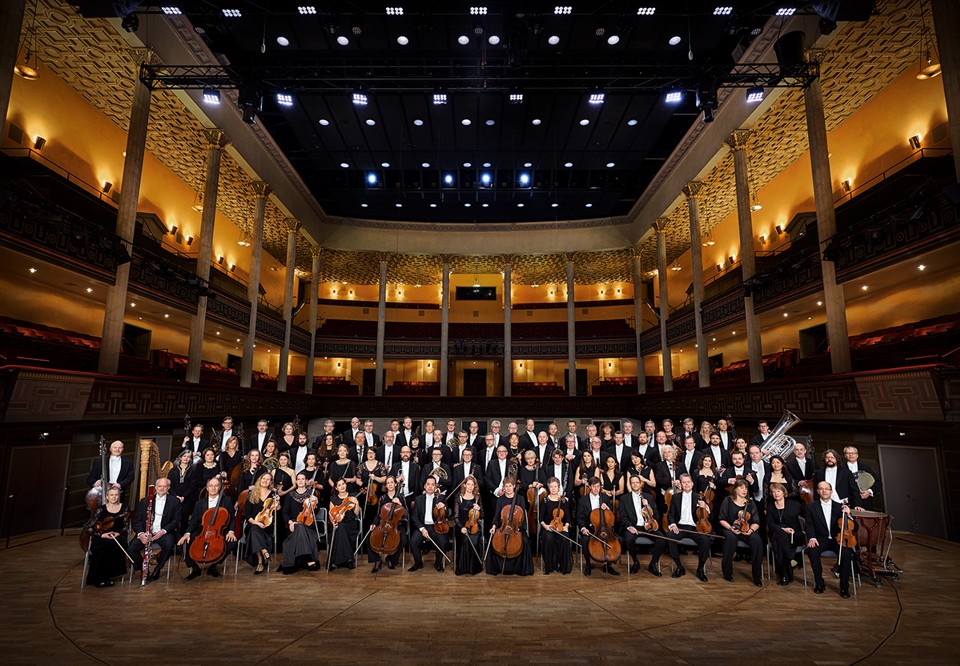 Gruppbild på hela orkestern i konsertkläder.