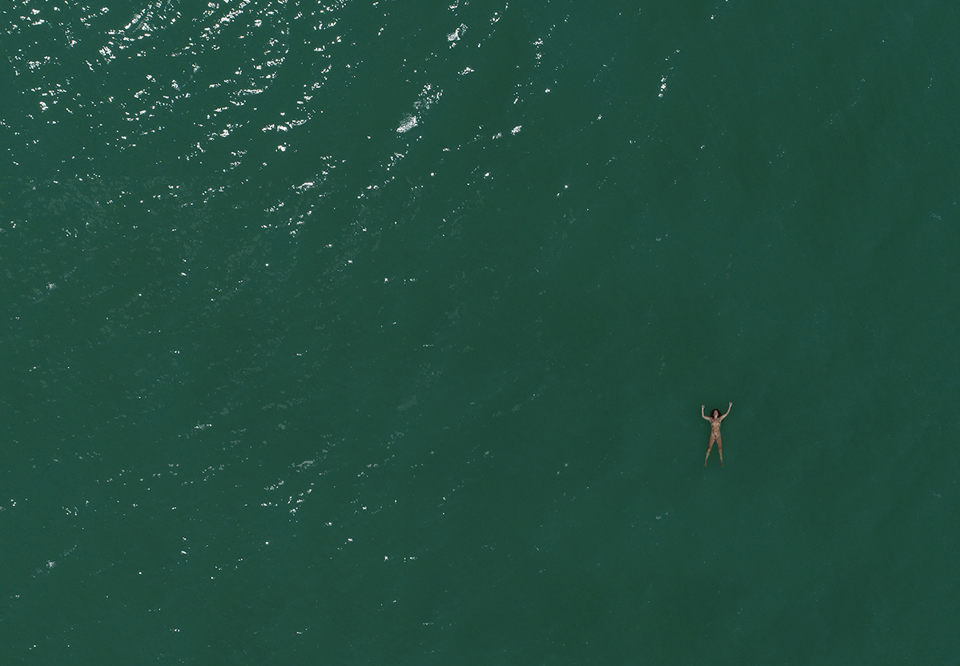Kvinna som ligger i ett grönt hav. Fotografi.