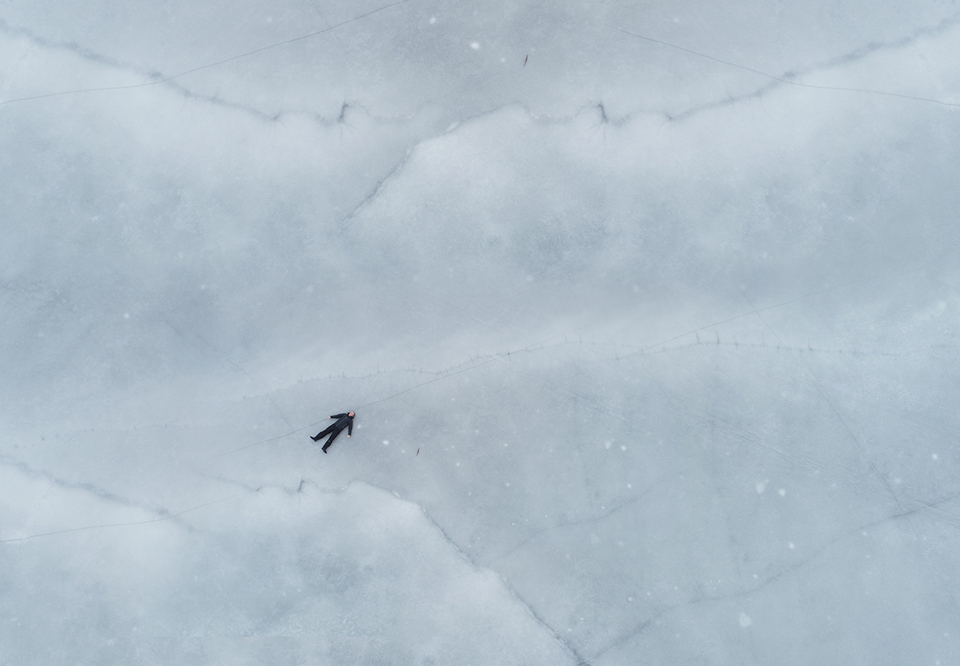 Man som ligger på is. Fotografi.
