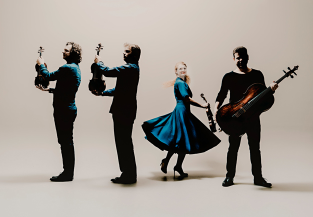 Four musicians, three men with string instruments and one woman. Photography.