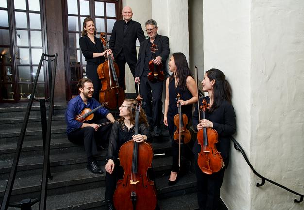 Picture of the whole ensemble standing together in a staircase.