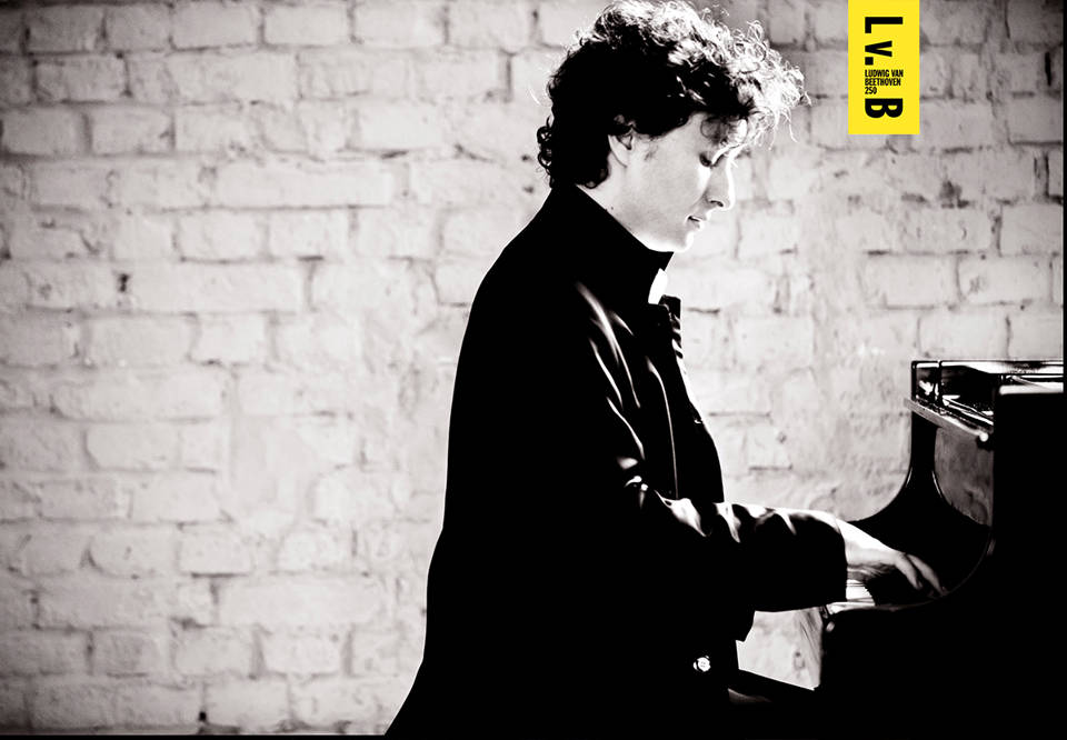Svartvitt fotografi med man spelandes på piano. bild tagen från sidan.