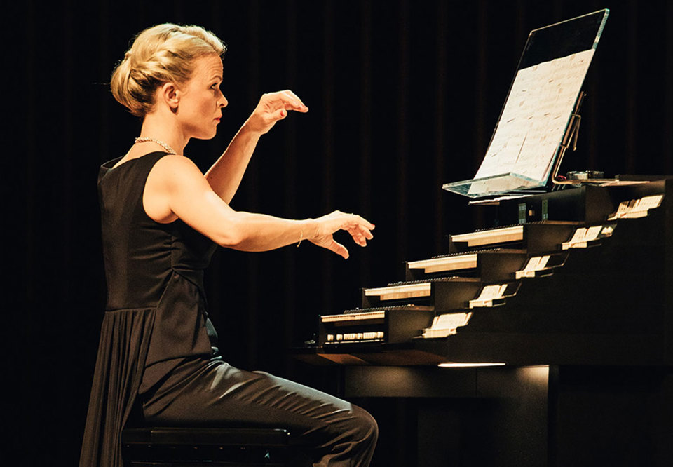 Woman in dark clothes playing her organ.