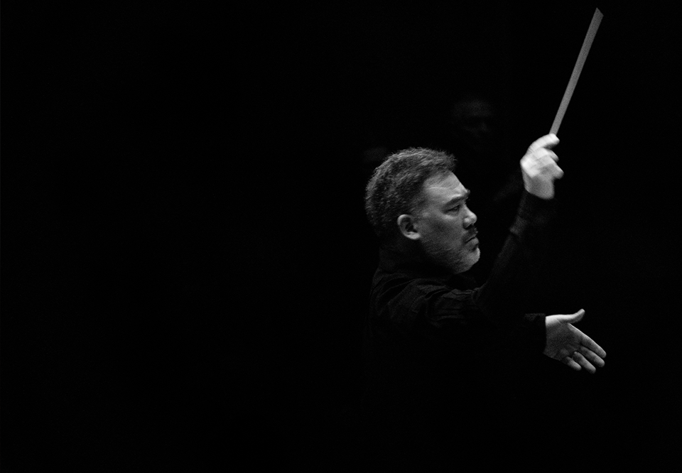 Black and white photo of a conducting man. 