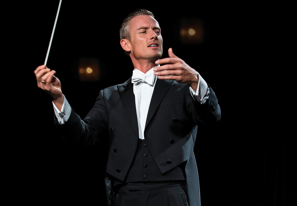 Man conducting on stage. Photo.