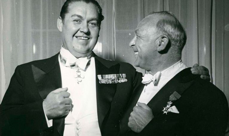 Två skrattande män klädda i frack. Jussi Björling och Carl Garaguly, glada och uppklädda, i samband med nyårskonserten den 31 december 1944. Fotografi.