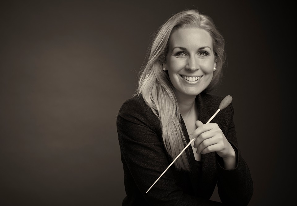 Kvinna som håller i en dirigentpinne. Fotografi.