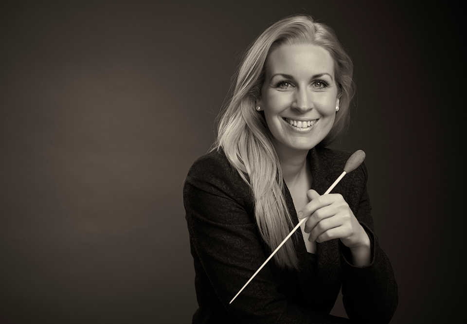 Kvinna som ler och håller i en dirigentpinne