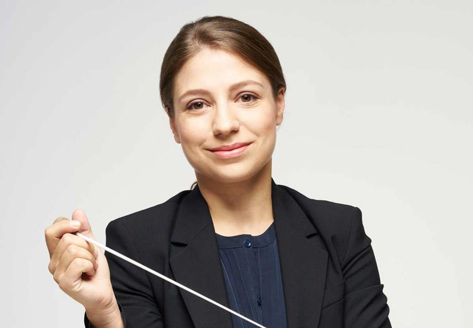 Unga kvinna som håller i en dirigentpinne. Fotografi.