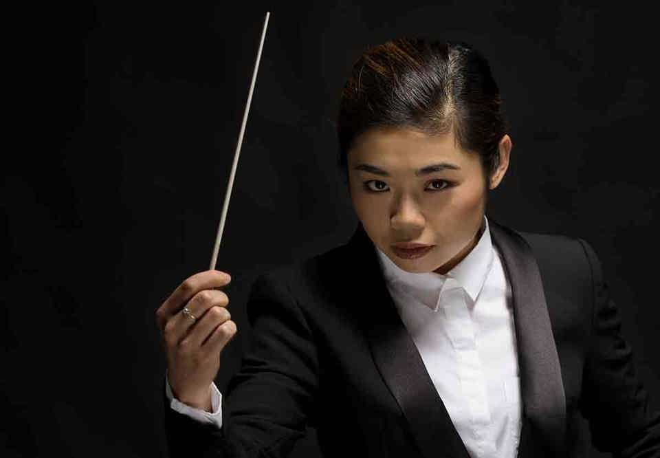 Närbild, porträtt på dirigenten med pinnen i handen. Foto.