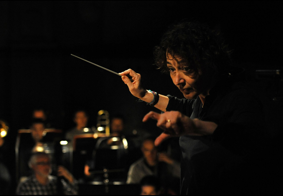 Actionbild på dirigent som har båda händerna mot orkestern. Nathalie Stutzmann. Fotografi.