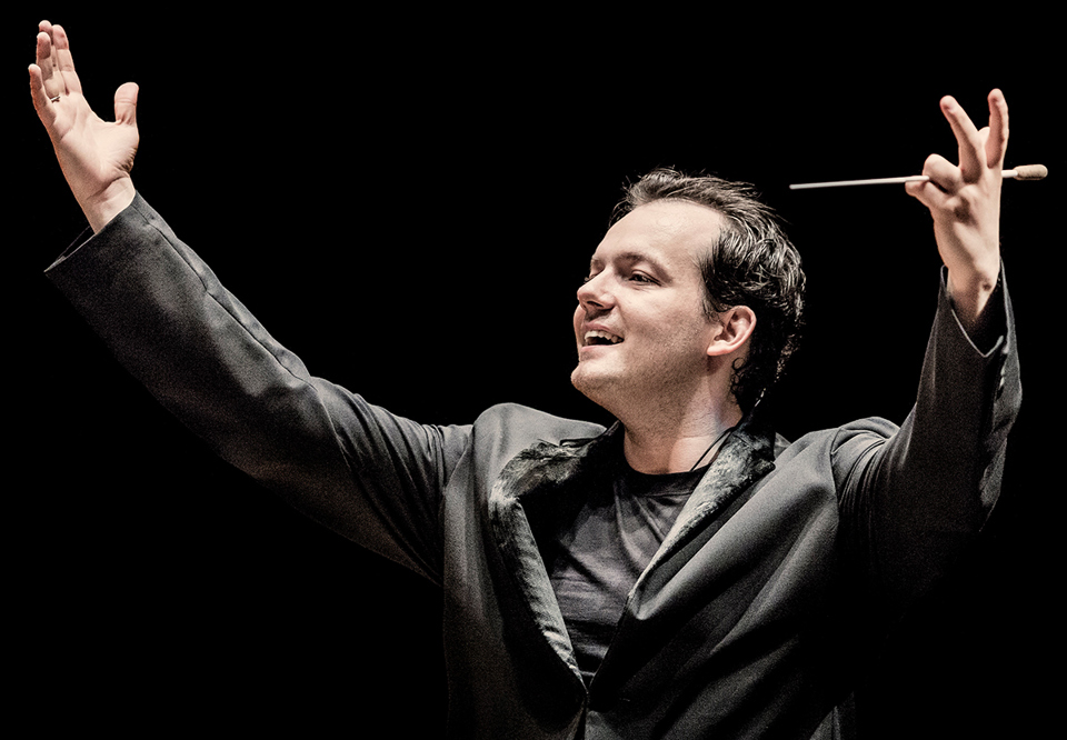 Conductor with black clothes and his hands in the air. Photo.