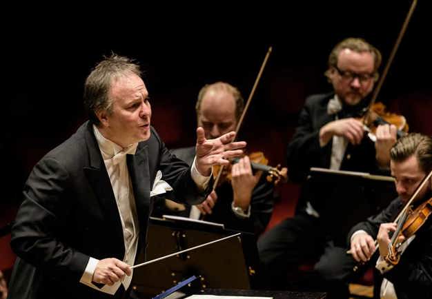 Man conducting on stage. Photo.